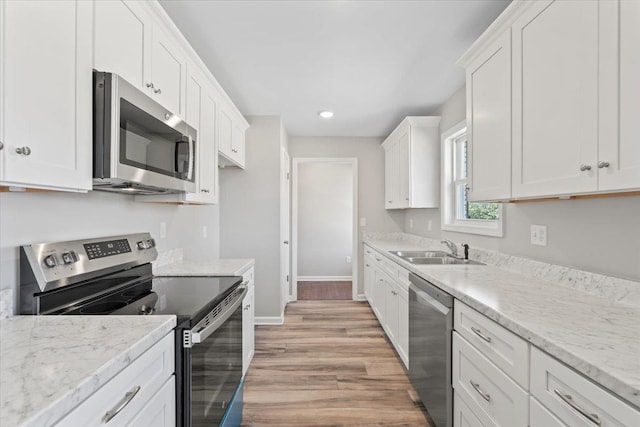 kitchen featuring white cabinets, stainless steel appliances, baseboards, and a sink