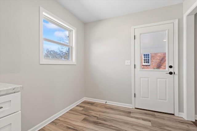 doorway with light wood-type flooring and baseboards