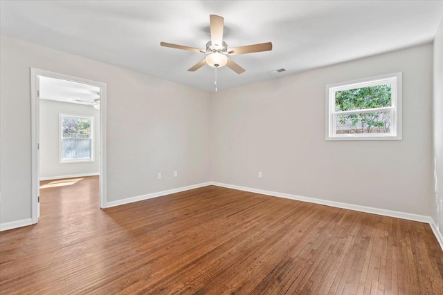 empty room featuring baseboards, wood-type flooring, visible vents, and a ceiling fan