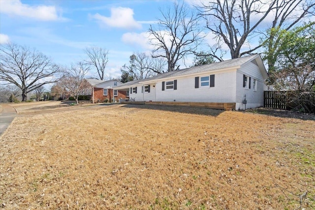 single story home featuring brick siding, a front lawn, and fence