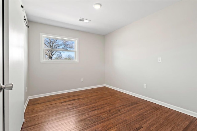 spare room featuring visible vents, wood finished floors, and baseboards