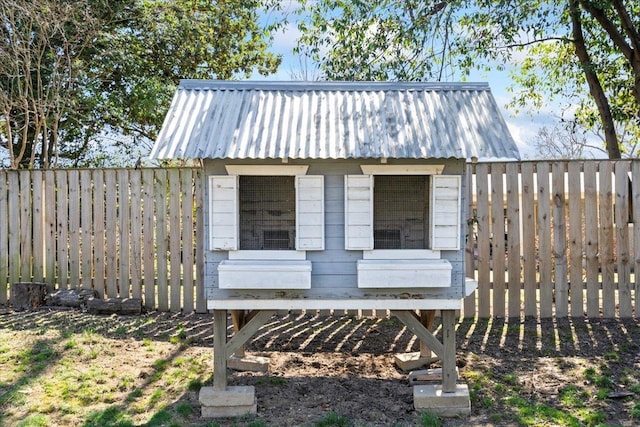 view of front of home with exterior structure, metal roof, an outdoor structure, and fence