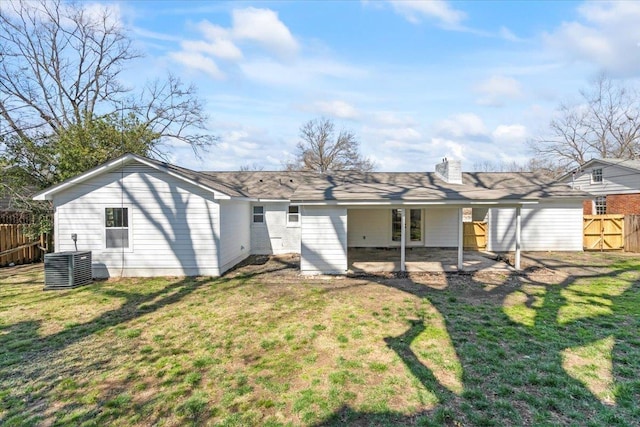 rear view of house with fence, central air condition unit, a chimney, a yard, and a patio