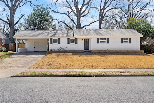 ranch-style house with brick siding, an attached carport, concrete driveway, and a front lawn