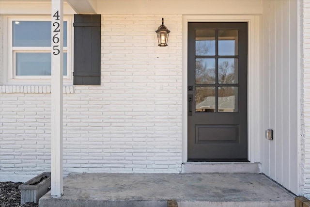 view of exterior entry featuring brick siding