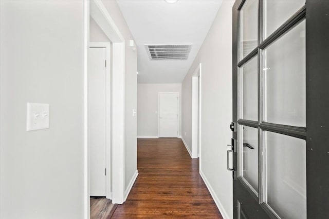 hallway featuring visible vents, baseboards, and dark wood finished floors