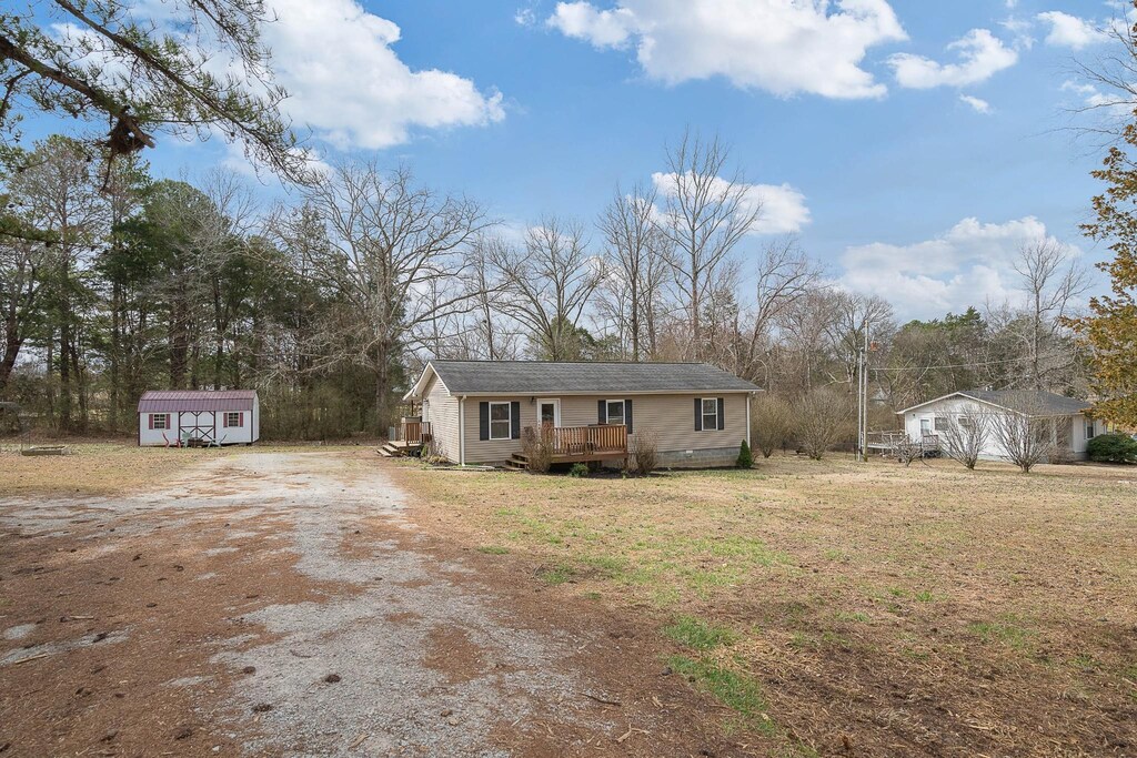 view of front of property featuring an outdoor structure, a shed, driveway, and a wooden deck