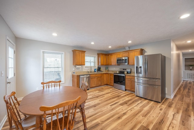 kitchen featuring light wood-type flooring, stainless steel appliances, brown cabinets, and light countertops