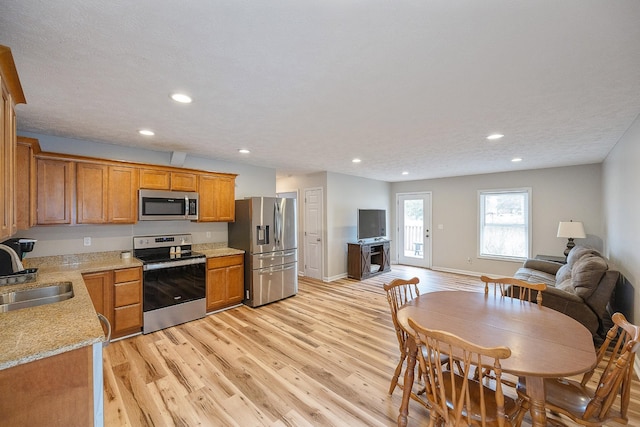 kitchen featuring a sink, stainless steel appliances, light wood-style floors, and open floor plan