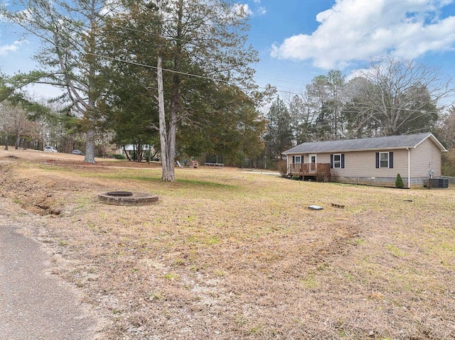 view of yard featuring a wooden deck, an outdoor fire pit, and central AC