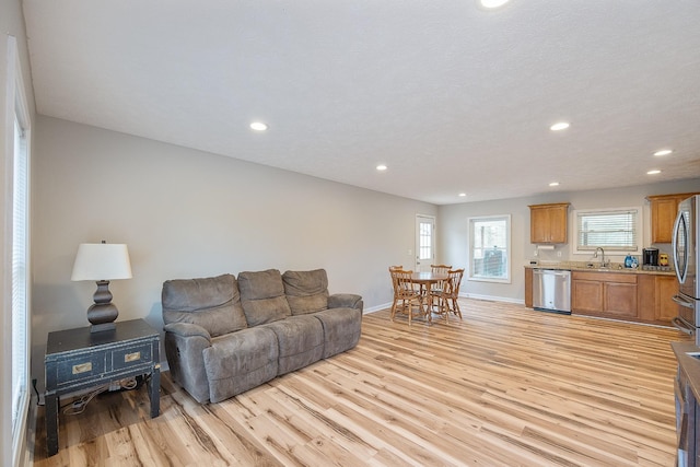 living room featuring recessed lighting, baseboards, and light wood-style floors