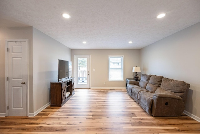 living area featuring recessed lighting, a textured ceiling, light wood-type flooring, and baseboards