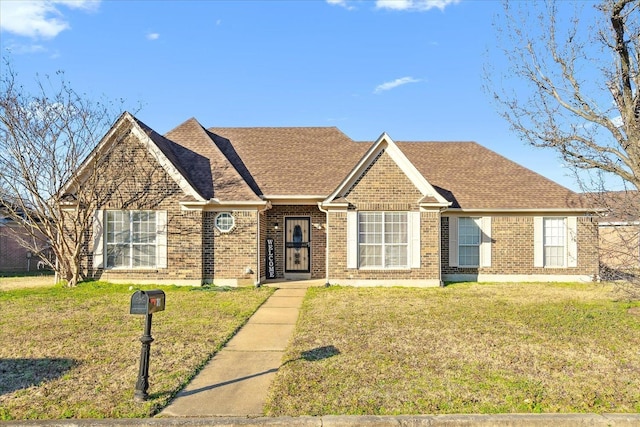 ranch-style home featuring brick siding, roof with shingles, and a front lawn