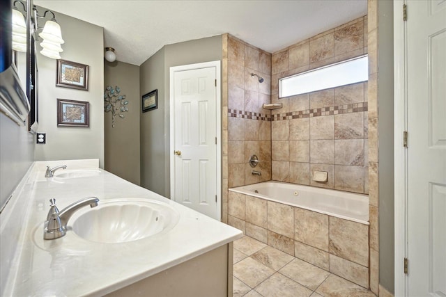 bathroom featuring tile patterned flooring, double vanity, tiled shower / bath combo, a textured ceiling, and a sink