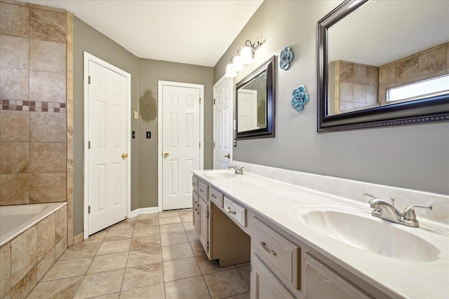 full bathroom with tiled bath, tile patterned floors, double vanity, and a sink