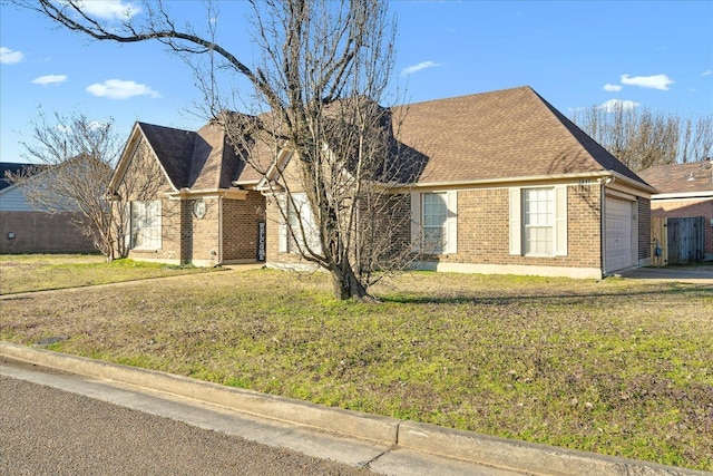 view of front of property featuring an attached garage, brick siding, roof with shingles, and a front lawn