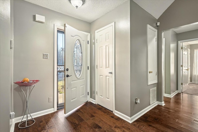 foyer featuring visible vents, a textured ceiling, baseboards, and hardwood / wood-style flooring