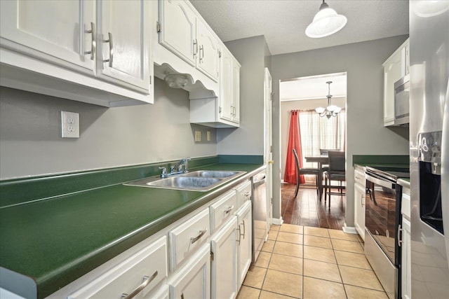 kitchen featuring light tile patterned flooring, white cabinets, a textured ceiling, and stainless steel appliances