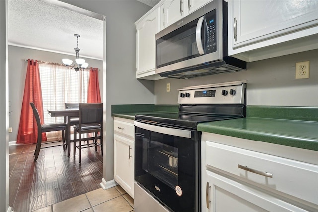 kitchen featuring stainless steel appliances, a textured ceiling, white cabinetry, dark countertops, and a chandelier