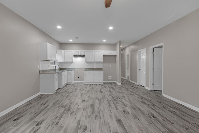 kitchen with baseboards, decorative backsplash, light wood-style flooring, white cabinets, and a sink