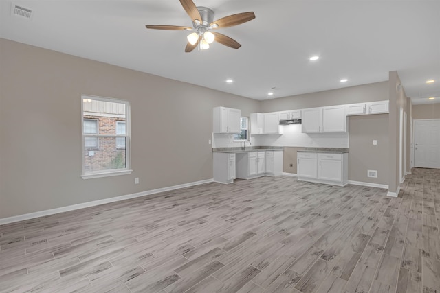 kitchen with baseboards, visible vents, a sink, light wood-style floors, and white cabinetry