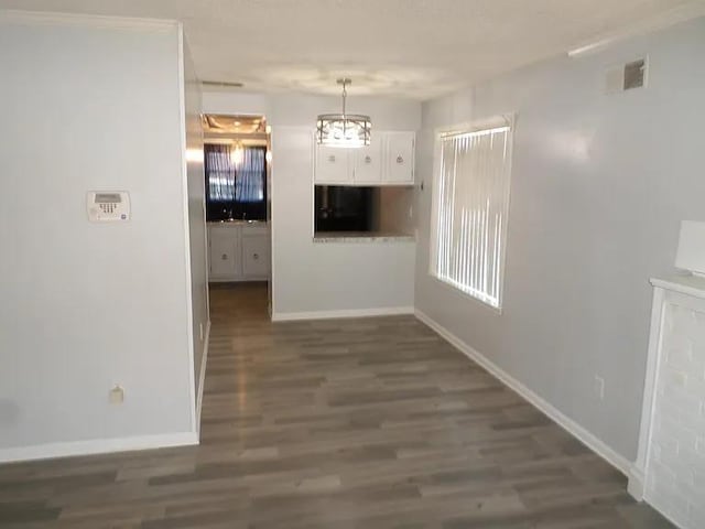 unfurnished dining area with baseboards, visible vents, dark wood-style flooring, and a sink