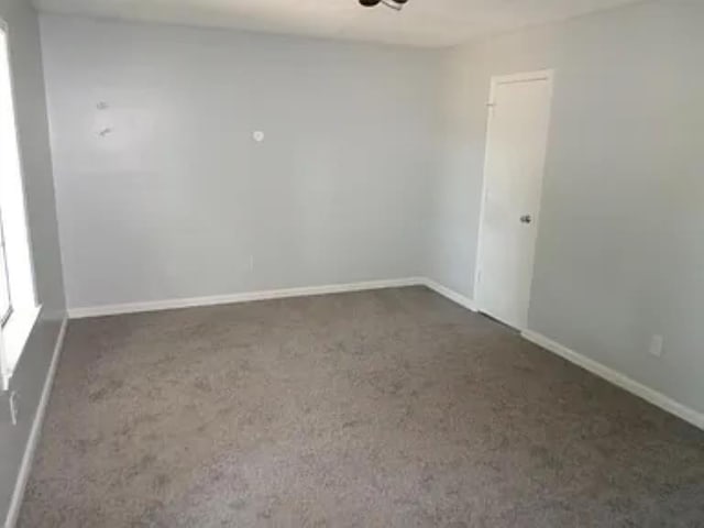 unfurnished room with carpet and baseboards