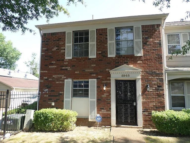 view of front facade featuring fence and brick siding