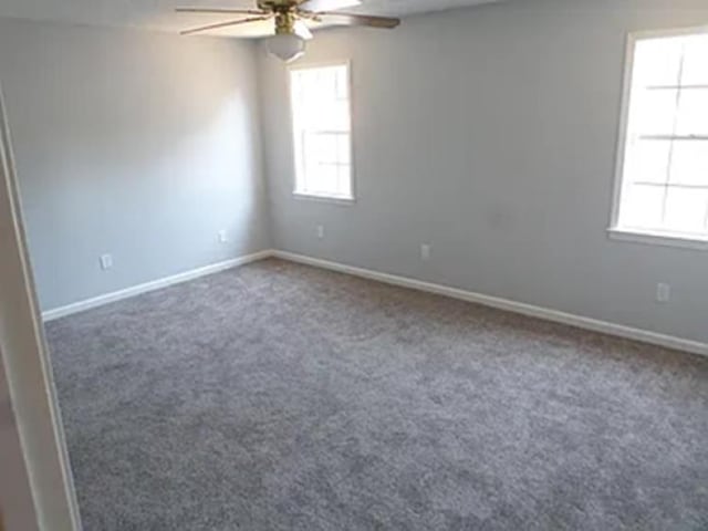 unfurnished room with carpet flooring, ceiling fan, and baseboards