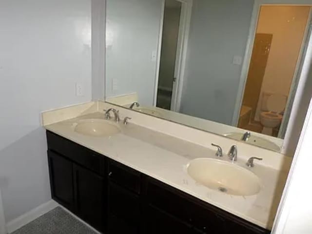 full bathroom with a sink, baseboards, and double vanity