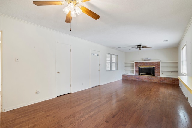 unfurnished living room with a ceiling fan, crown molding, a brick fireplace, and wood finished floors