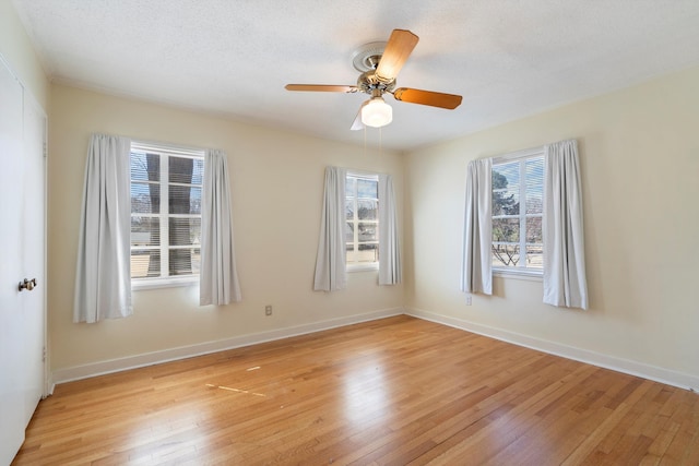 unfurnished room featuring ceiling fan, light wood-style floors, baseboards, and a healthy amount of sunlight