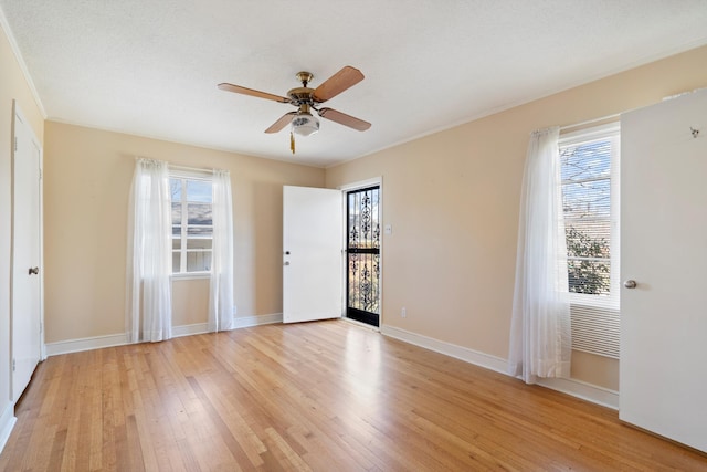 spare room with a wealth of natural light, baseboards, and light wood finished floors