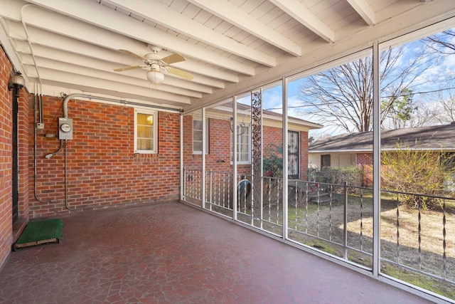 unfurnished sunroom featuring beamed ceiling and ceiling fan