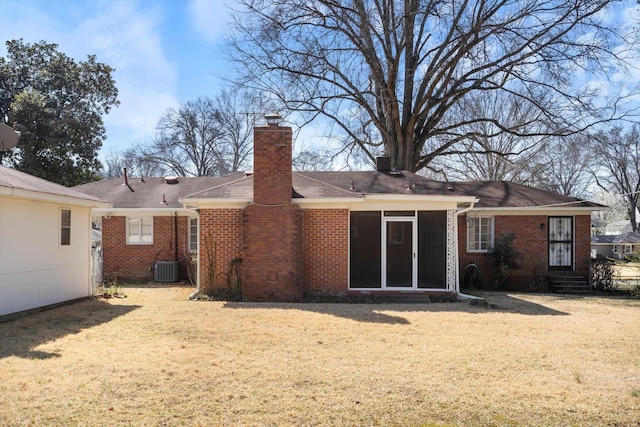 rear view of house with brick siding, a chimney, and a yard