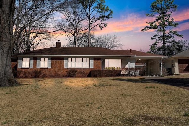 ranch-style home with a yard, brick siding, and a chimney