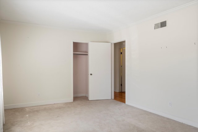 unfurnished bedroom with carpet, visible vents, baseboards, a closet, and crown molding