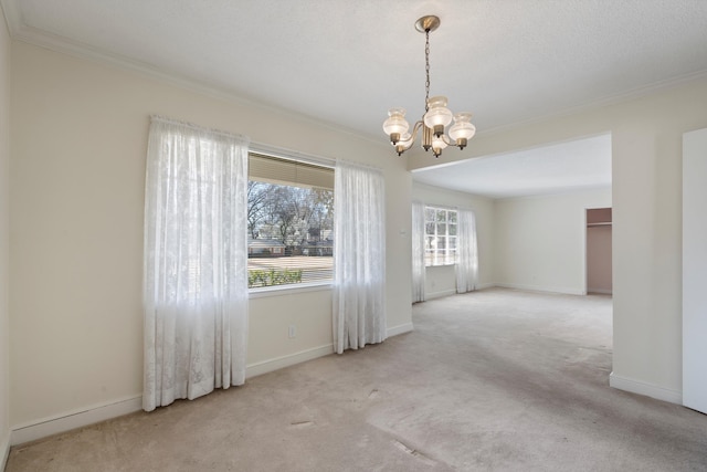 carpeted spare room with baseboards, a chandelier, and ornamental molding