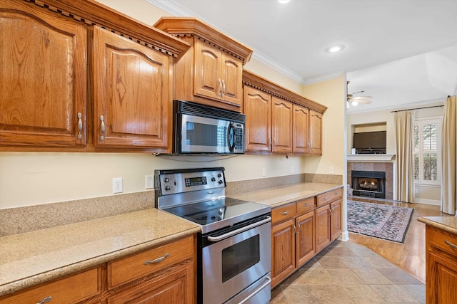 kitchen featuring light countertops, brown cabinetry, appliances with stainless steel finishes, and ornamental molding