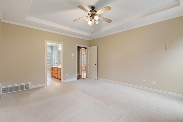 unfurnished bedroom featuring light carpet, visible vents, baseboards, and a tray ceiling