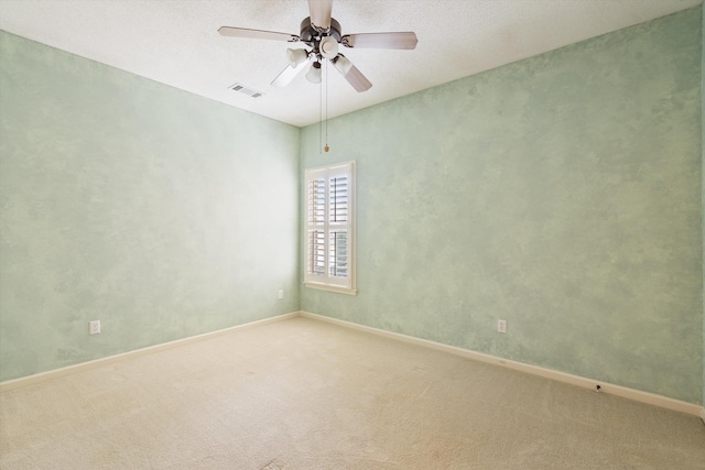 carpeted empty room with visible vents, baseboards, and ceiling fan