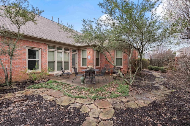 rear view of property featuring a patio area, brick siding, and a shingled roof