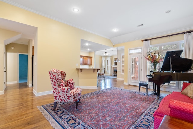 living area with crown molding, light wood-style flooring, baseboards, and visible vents