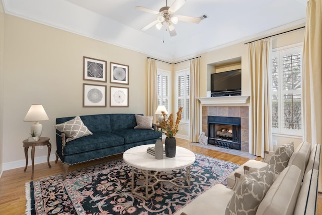 living area with a healthy amount of sunlight, a ceiling fan, baseboards, and wood finished floors