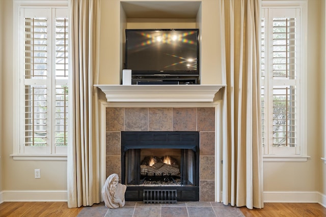 room details featuring baseboards, wood finished floors, and a tiled fireplace