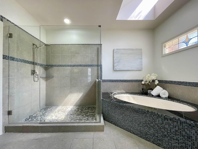 bathroom featuring tile patterned flooring, a shower stall, a skylight, and a garden tub