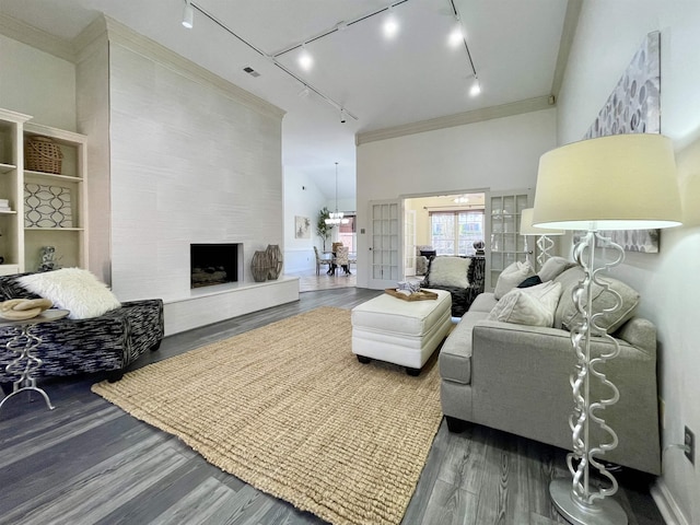 living area featuring visible vents, crown molding, a premium fireplace, a towering ceiling, and wood finished floors