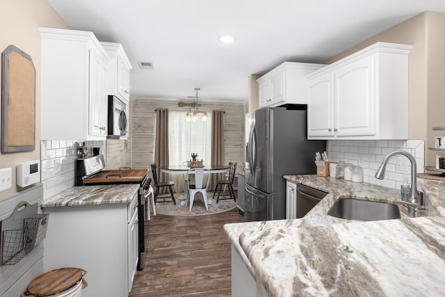 kitchen featuring visible vents, a sink, light stone counters, stainless steel appliances, and white cabinets