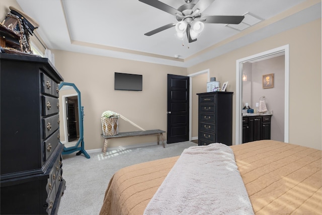 carpeted bedroom with ensuite bath, a ceiling fan, a raised ceiling, and baseboards