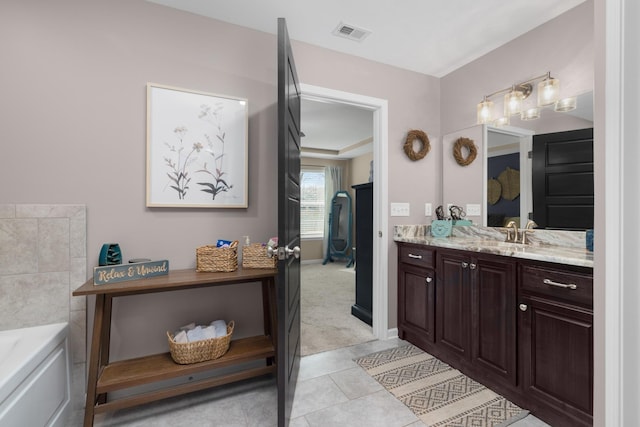 bathroom with tile patterned floors, visible vents, baseboards, a bath, and vanity